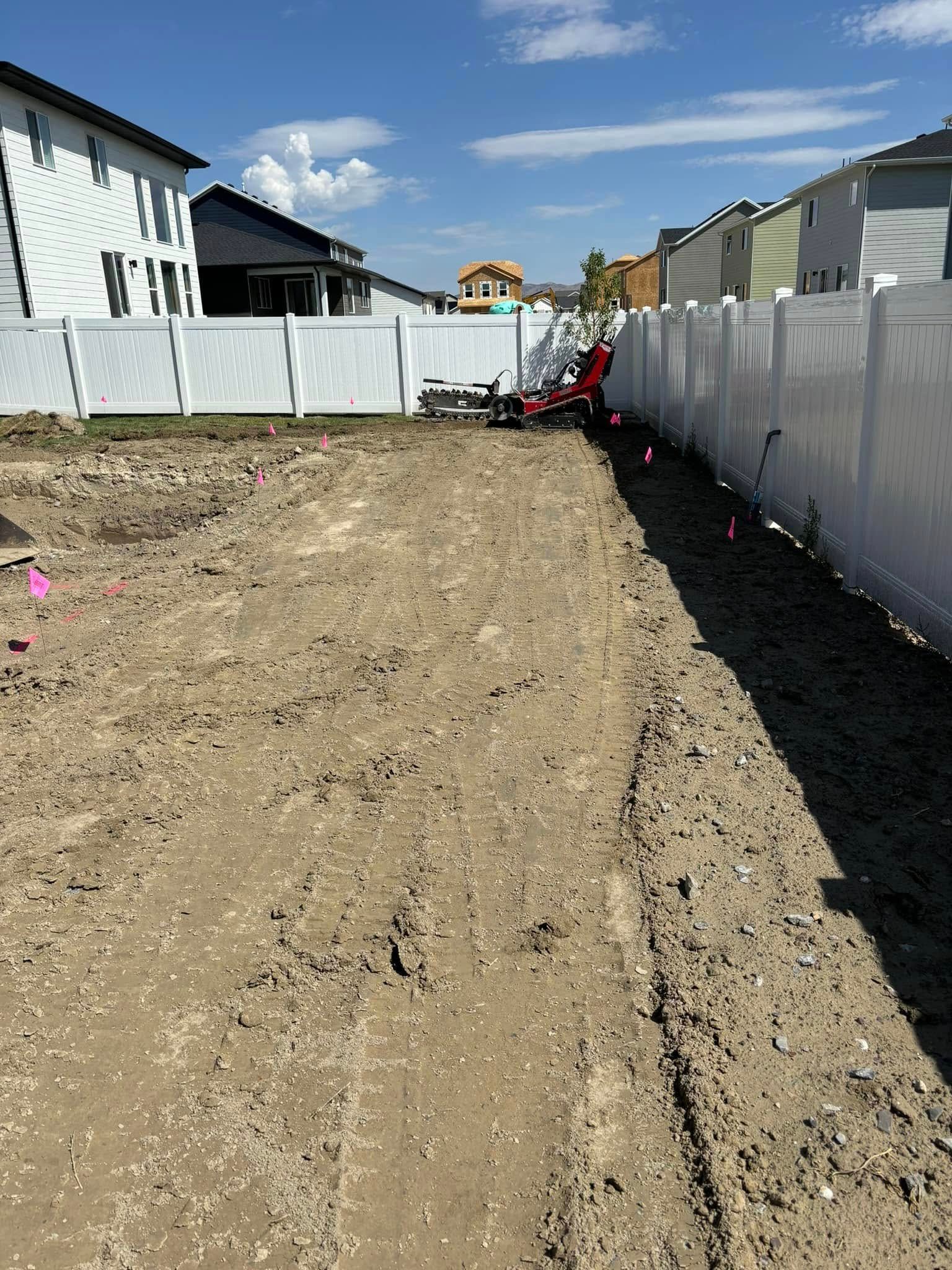 Judd Landscape & Curbing LLC | a dirt field with a white fence in the background.