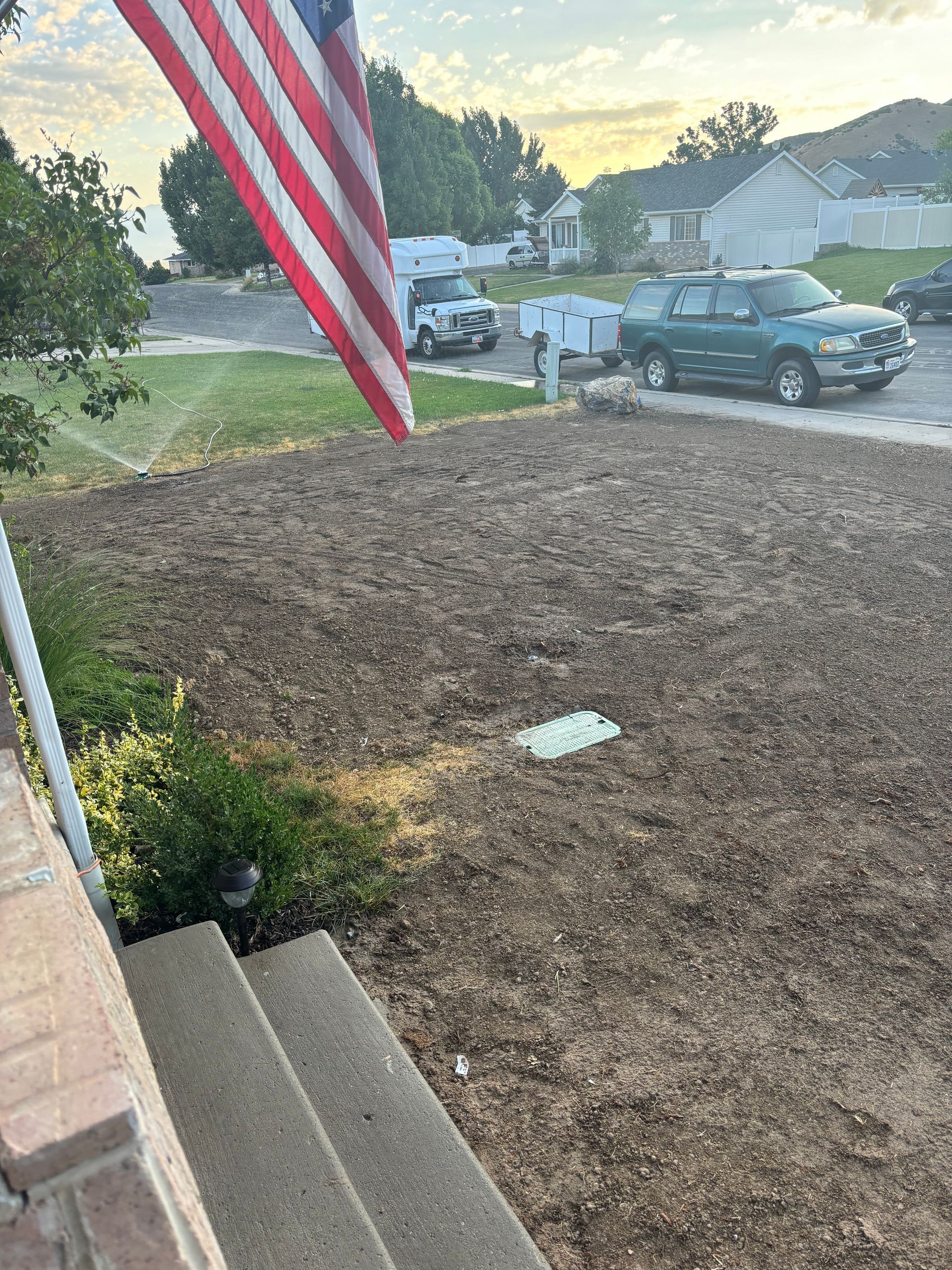 Judd Landscape & Curbing LLC | an American flag is flying in the wind in front of a house.