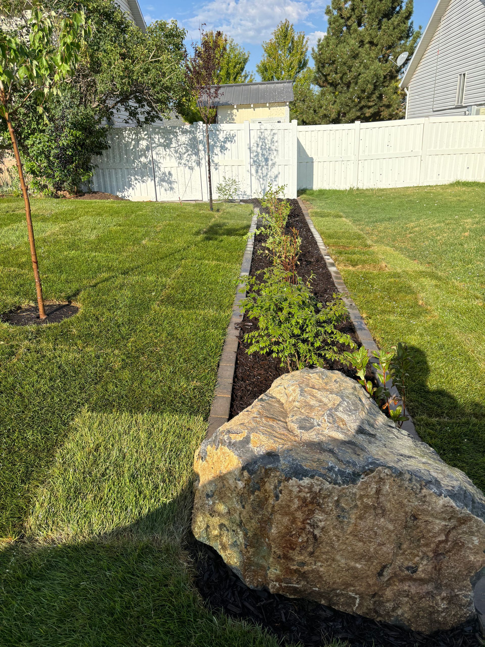 Judd Landscape & Curbing LLC | a large rock is sitting in the middle of a garden.
