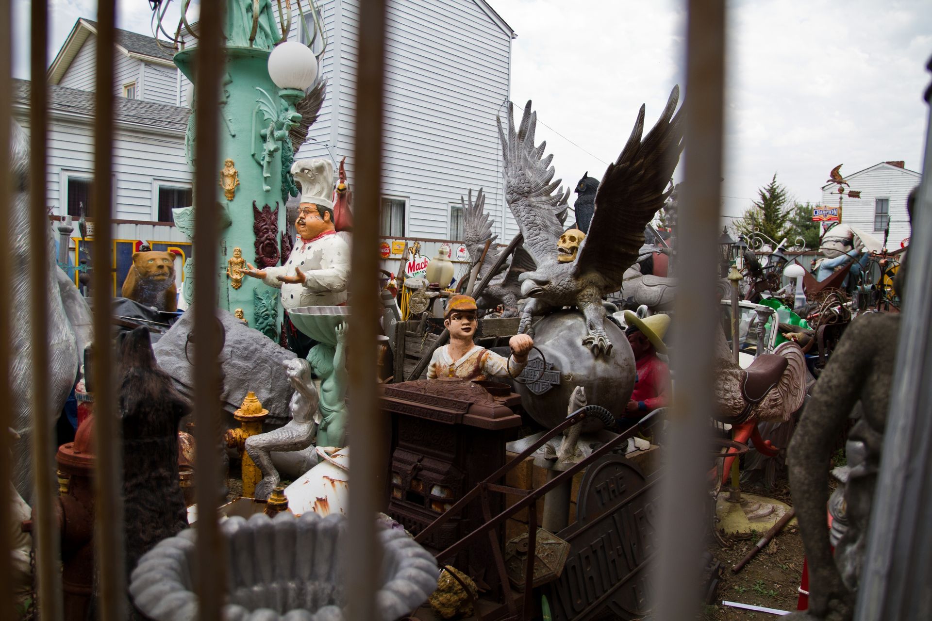 A bunch of statues are behind a fence in front of a building