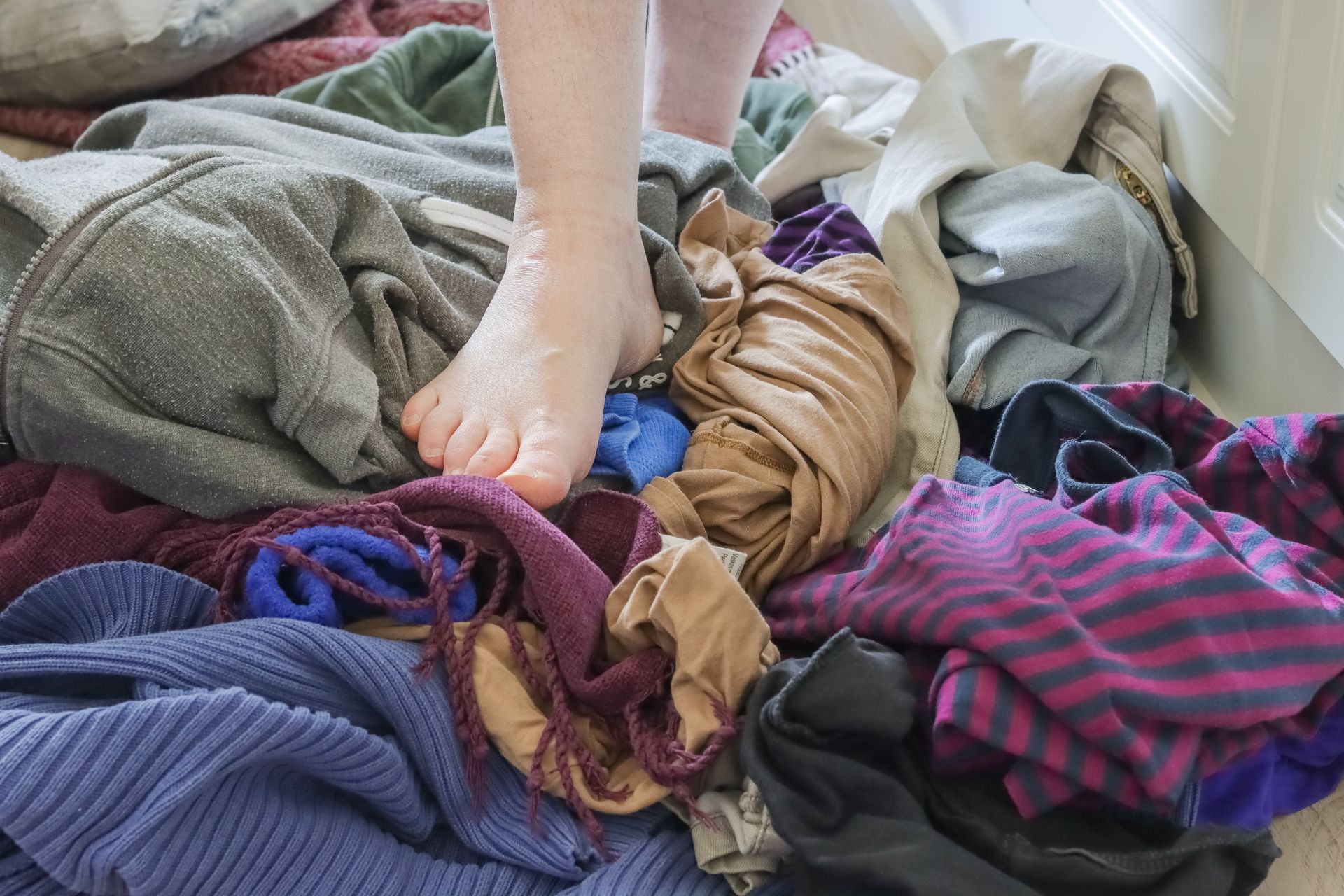 A person is standing on a pile of clothes.