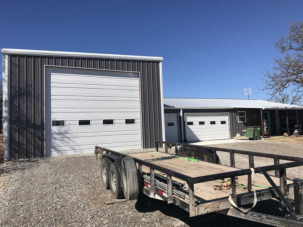 A trailer is parked in front of a garage door.