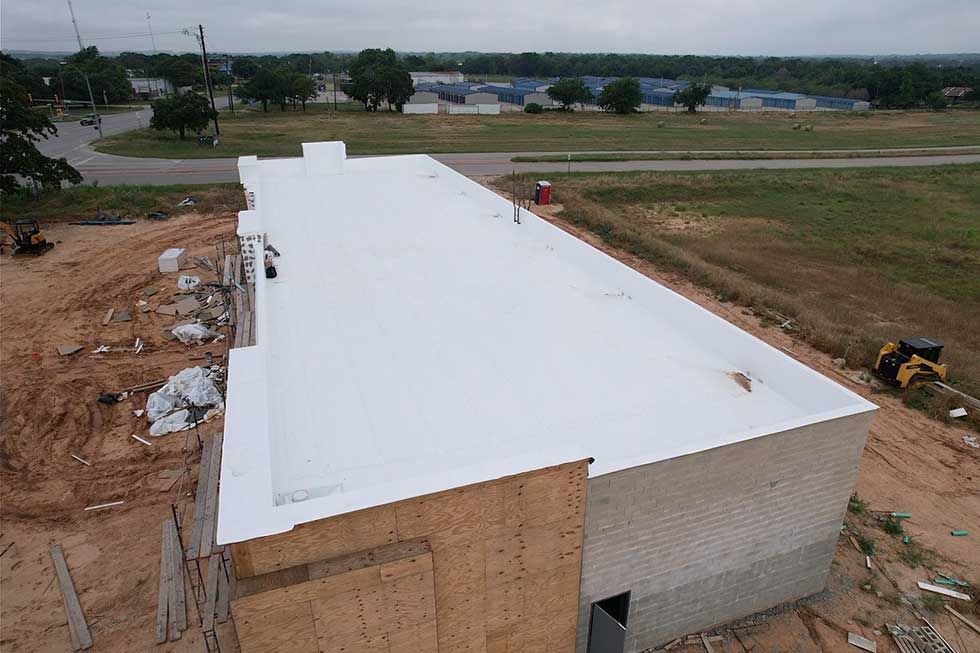 An aerial view of a building under construction with a white roof.