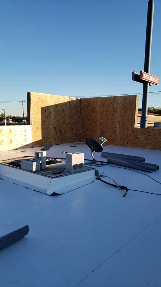 A satellite dish is sitting on top of a white roof.