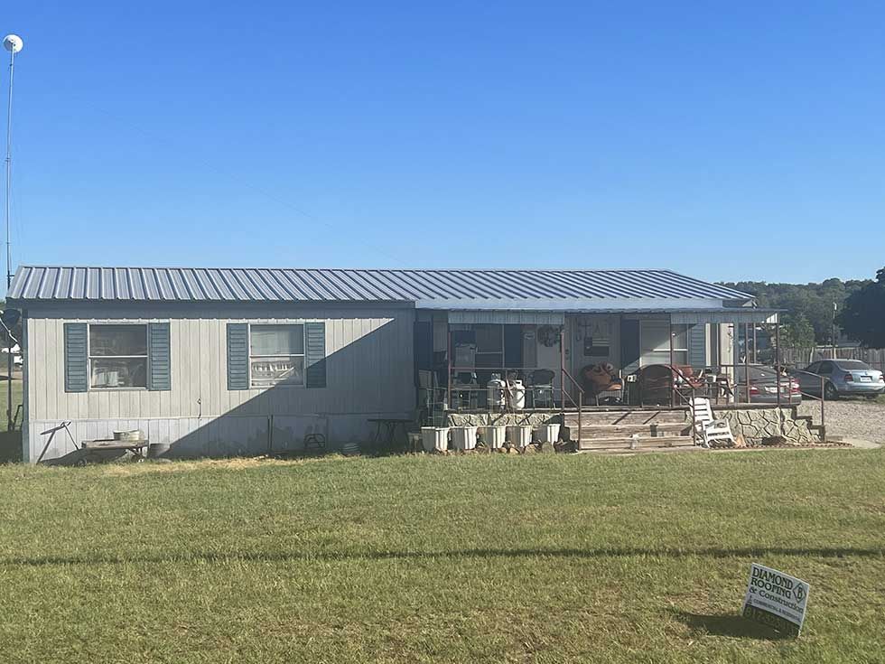 A mobile home is sitting in the middle of a grassy field.