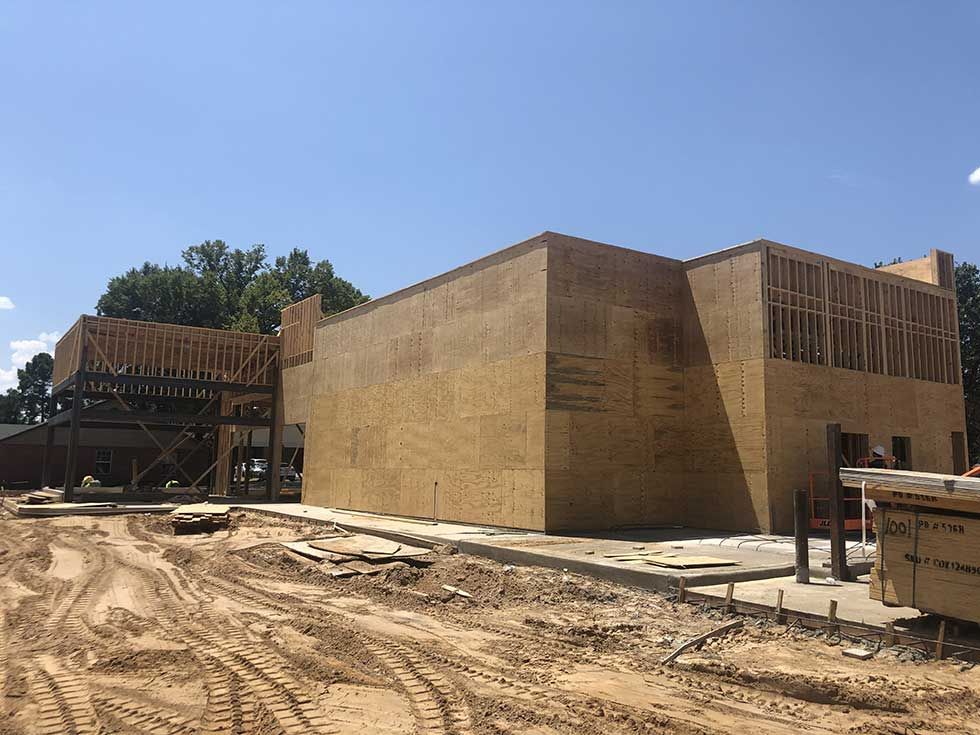 A large building is being built in a dirt field.