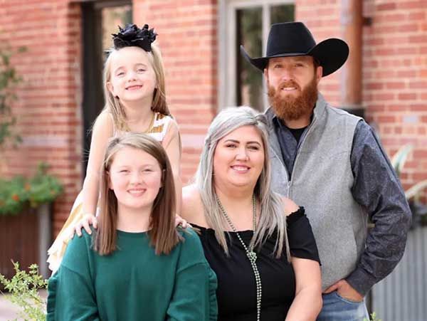 A family is posing for a picture in front of a brick building.
