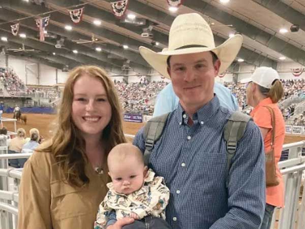 A man in a cowboy hat is holding a baby and a woman is holding a baby.