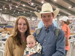A man in a cowboy hat is holding a baby and a woman is holding a baby.