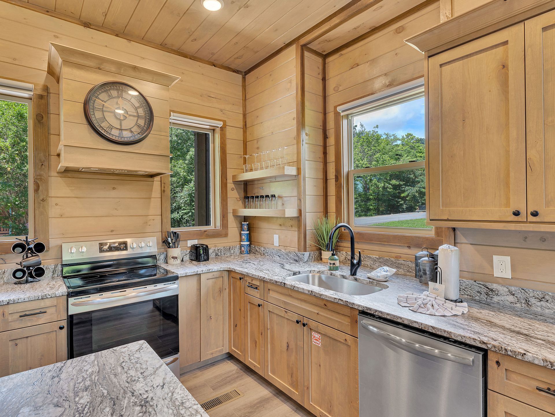 Cabin kitchen with wood paneling, granite countertops, and stainless steel appliances.