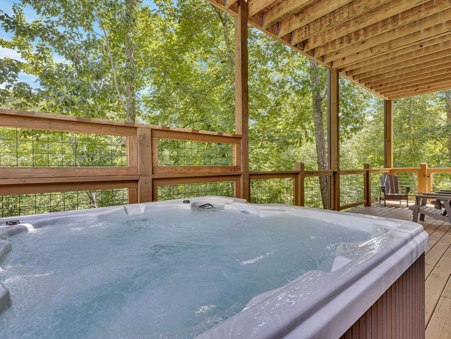 Hot tub on a wooden deck overlooking trees.