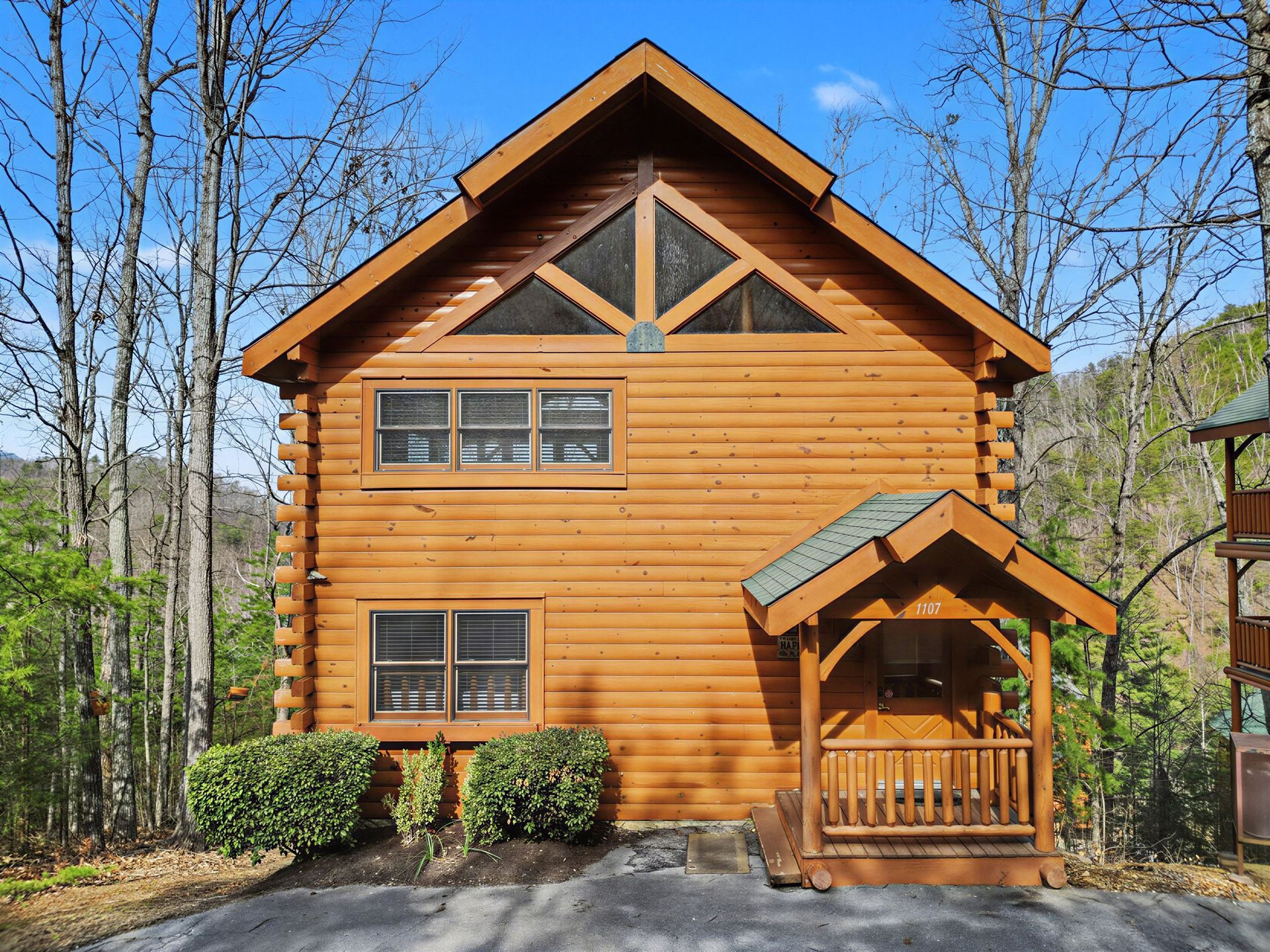 Log cabin with porch nestled among trees.