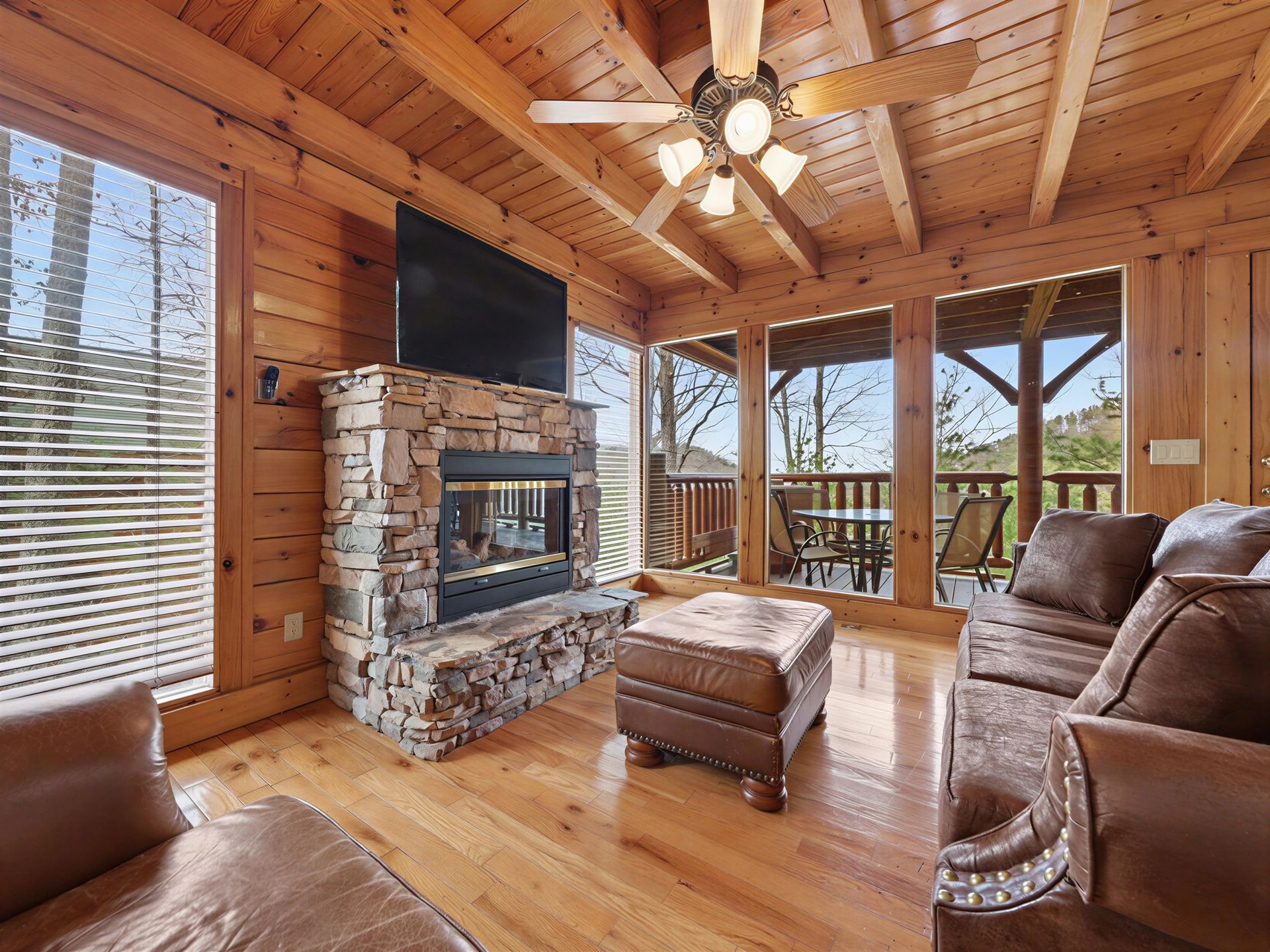 Cozy cabin living room with fireplace, windows, and sofa. Wooden walls and ceiling.