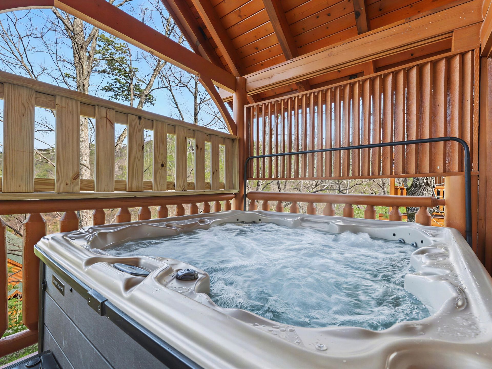 A bubbling hot tub on a wooden deck with a forest backdrop.