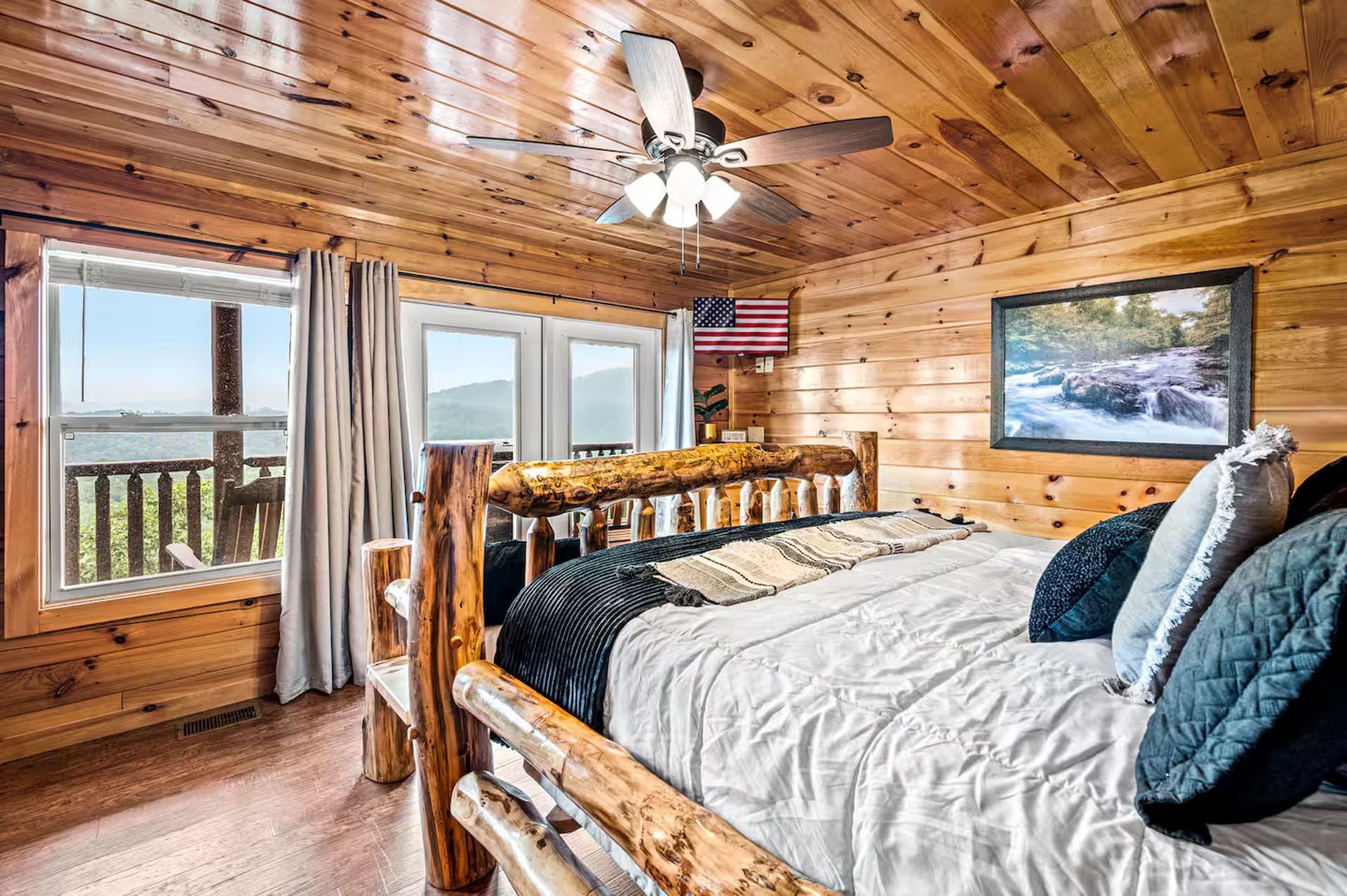 Cozy cabin bedroom with wood paneling, a log bed, and a window with a scenic view.