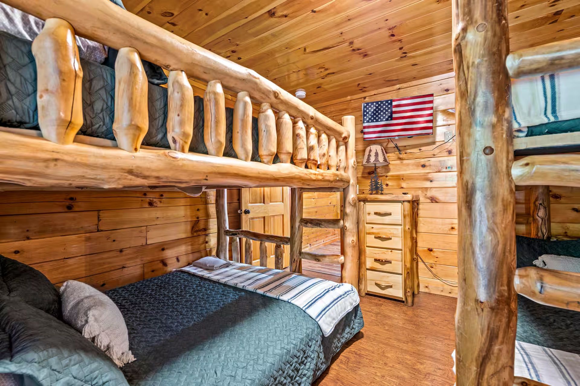 Bunk bed room with wooden walls, log accents, and an American flag.