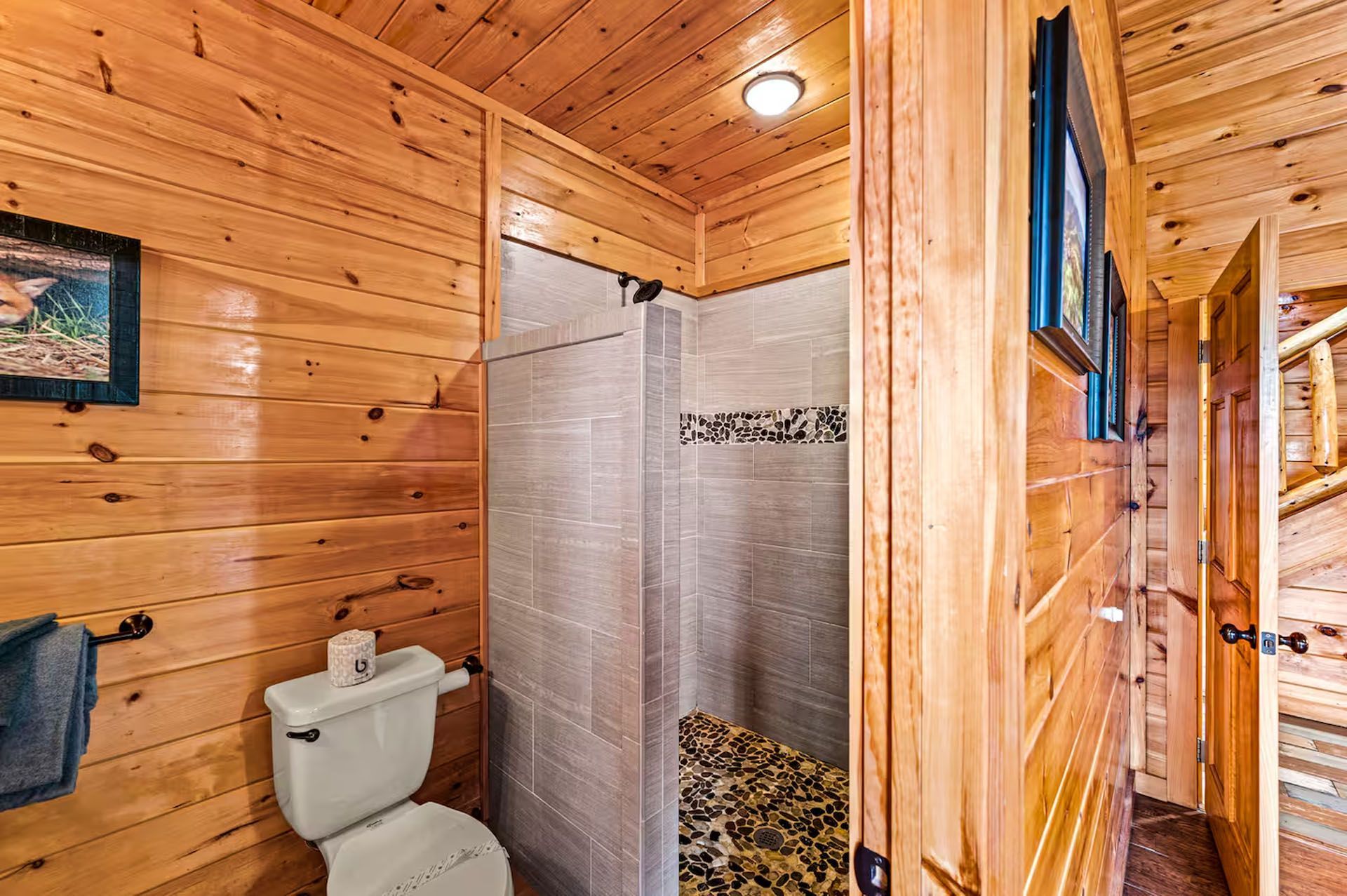 Bathroom with wood paneling, toilet, tiled shower, and open doorway.