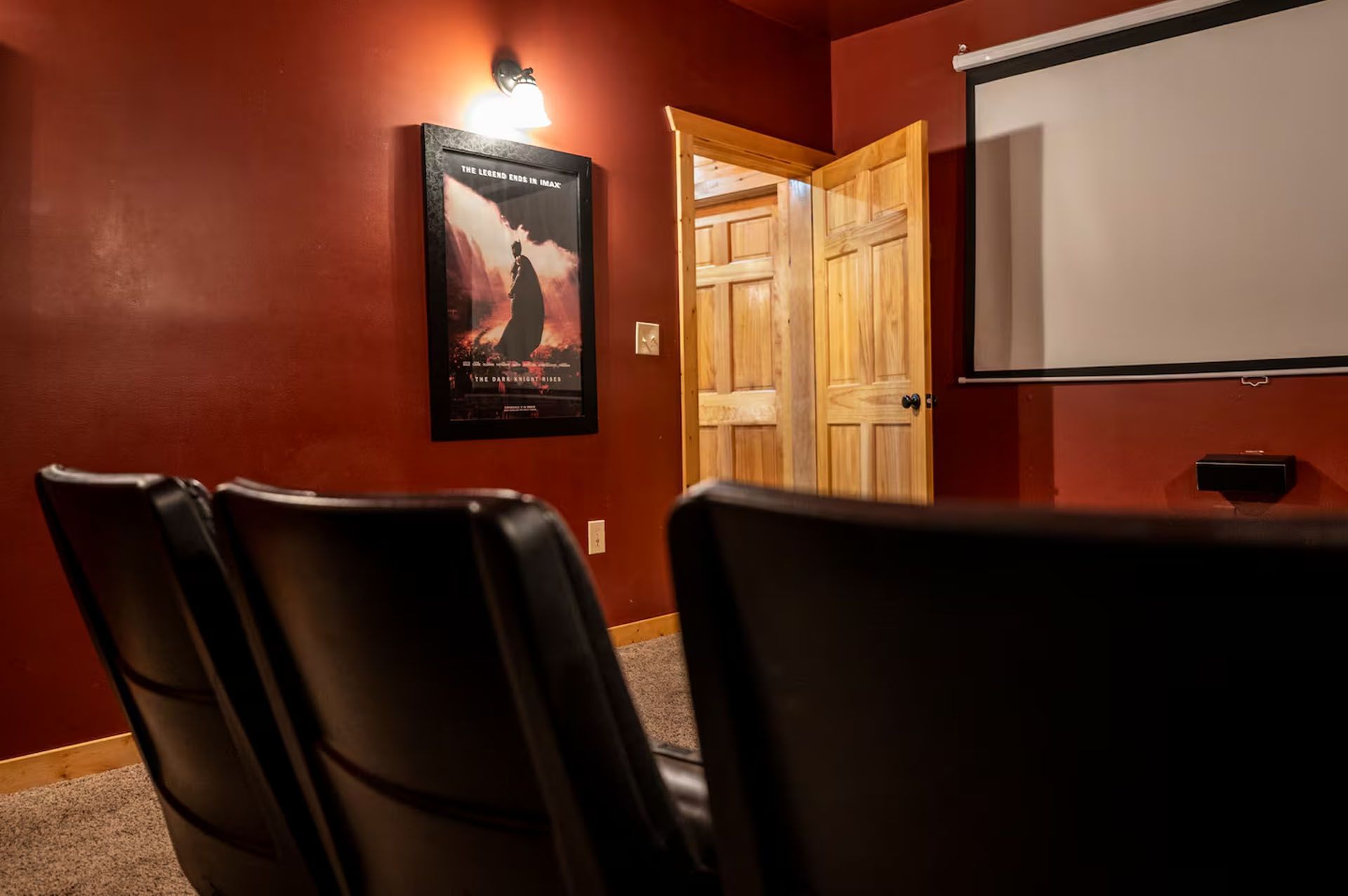 Movie theater room with burgundy walls, rows of black seats, and a projection screen.