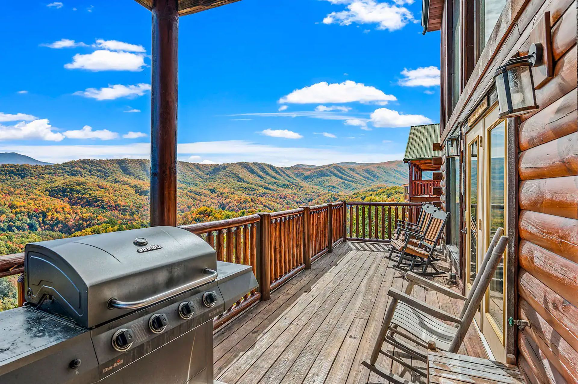 Deck overlooking a mountain view with grill and rocking chairs.