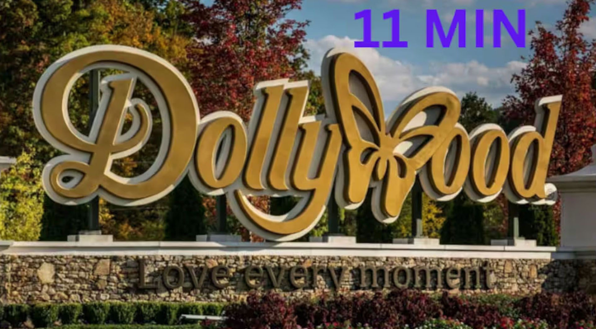 DollyWood sign with butterfly logo, surrounded by autumn trees.