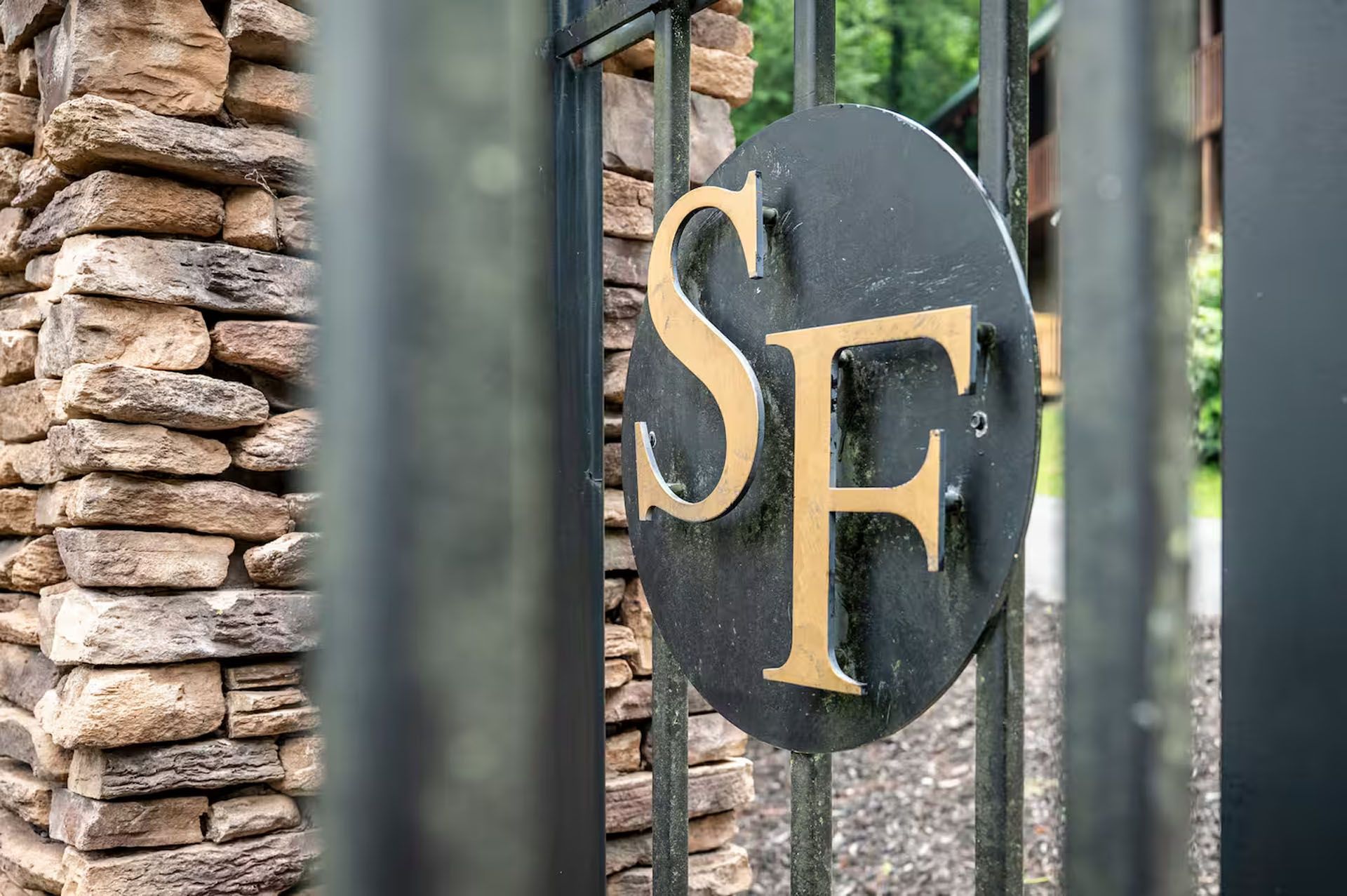 Black gate with stone pillar; gold SF emblem.