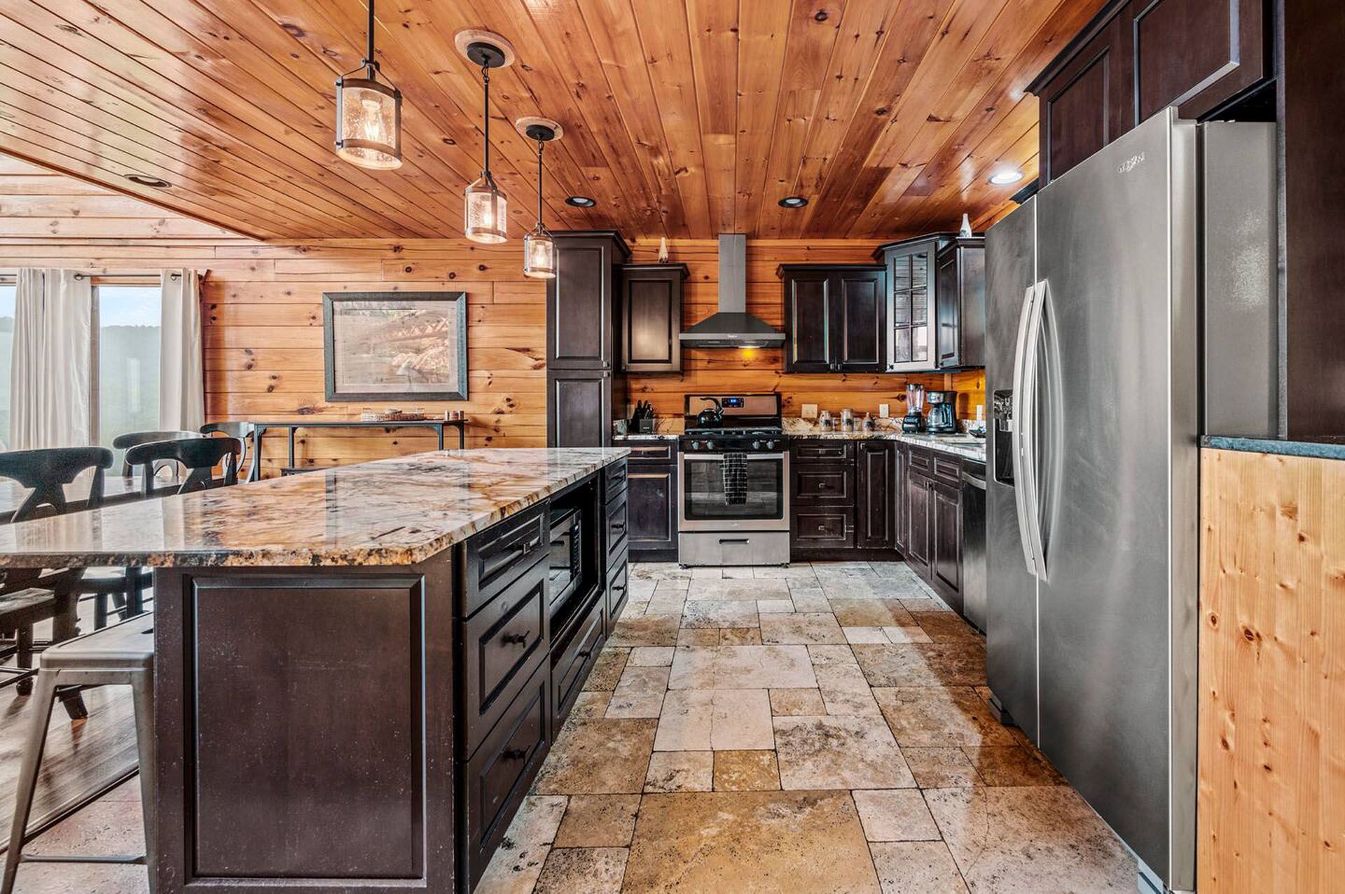 A modern kitchen with wood paneling, brown cabinets, granite island, and stainless steel appliances.