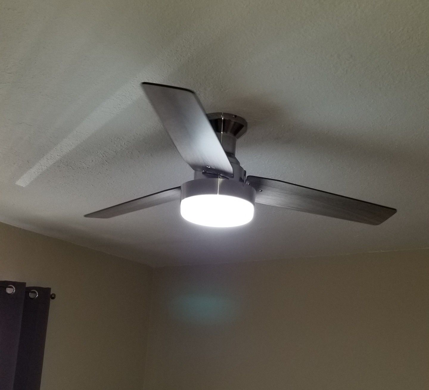 A man is installing a ceiling fan in a living room.