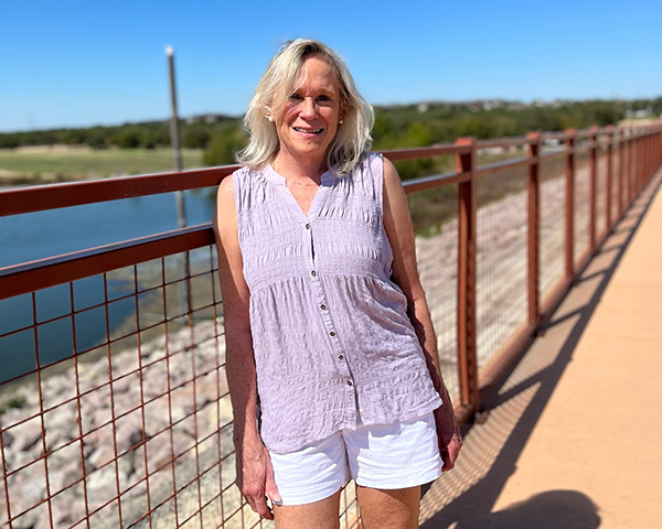 A woman is standing on a bridge overlooking a body of water.