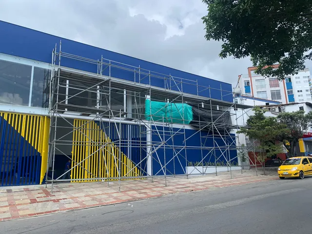 Se está construyendo un edificio azul y amarillo con andamios a su alrededor.