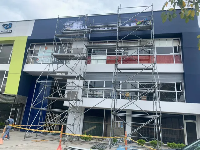 Un edificio azul y blanco con andamios delante.