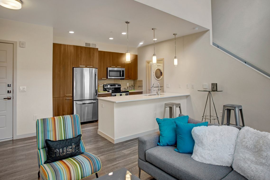 A living room with a couch , chair , table and kitchen.