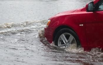 A Red Car Is Driving Through a Flooded Street — SVS Autocare in Kunda Park, QLD