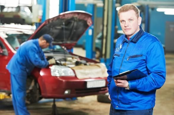 A Man in A Blue Jacket Is Standing Next to A Red Car in A Garage — SVS Autocare in Kunda Park, QLD