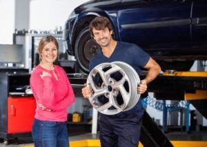 A Man and A Woman Are Standing Next to Each Other in A Garage Holding a Wheel — SVS Autocare in Kunda Park, QLD