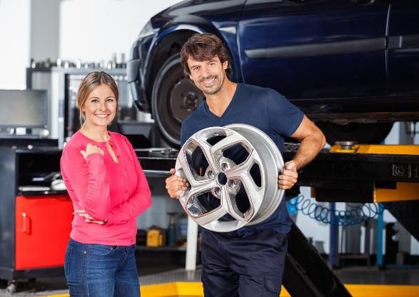 A Man and A Woman Are Holding a Car Wheel in A Garage — SVS Autocare in Kunda Park, QLD