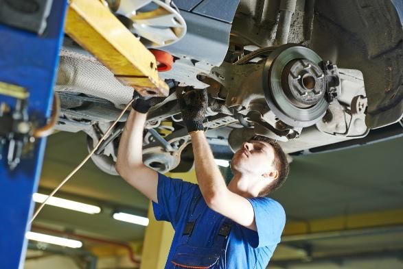 A Man Is Working on The Underside of A Car in A Garage — SVS Autocare in Kunda Park, QLD