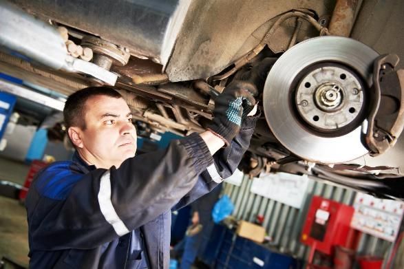 A Man Is Working Under a Car in A Garage — SVS Autocare in Kunda Park, QLD