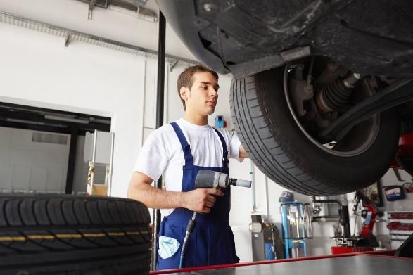 A Man Is Working on The Underside of A Car in A Garage — SVS Autocare in Kunda Park, QLD