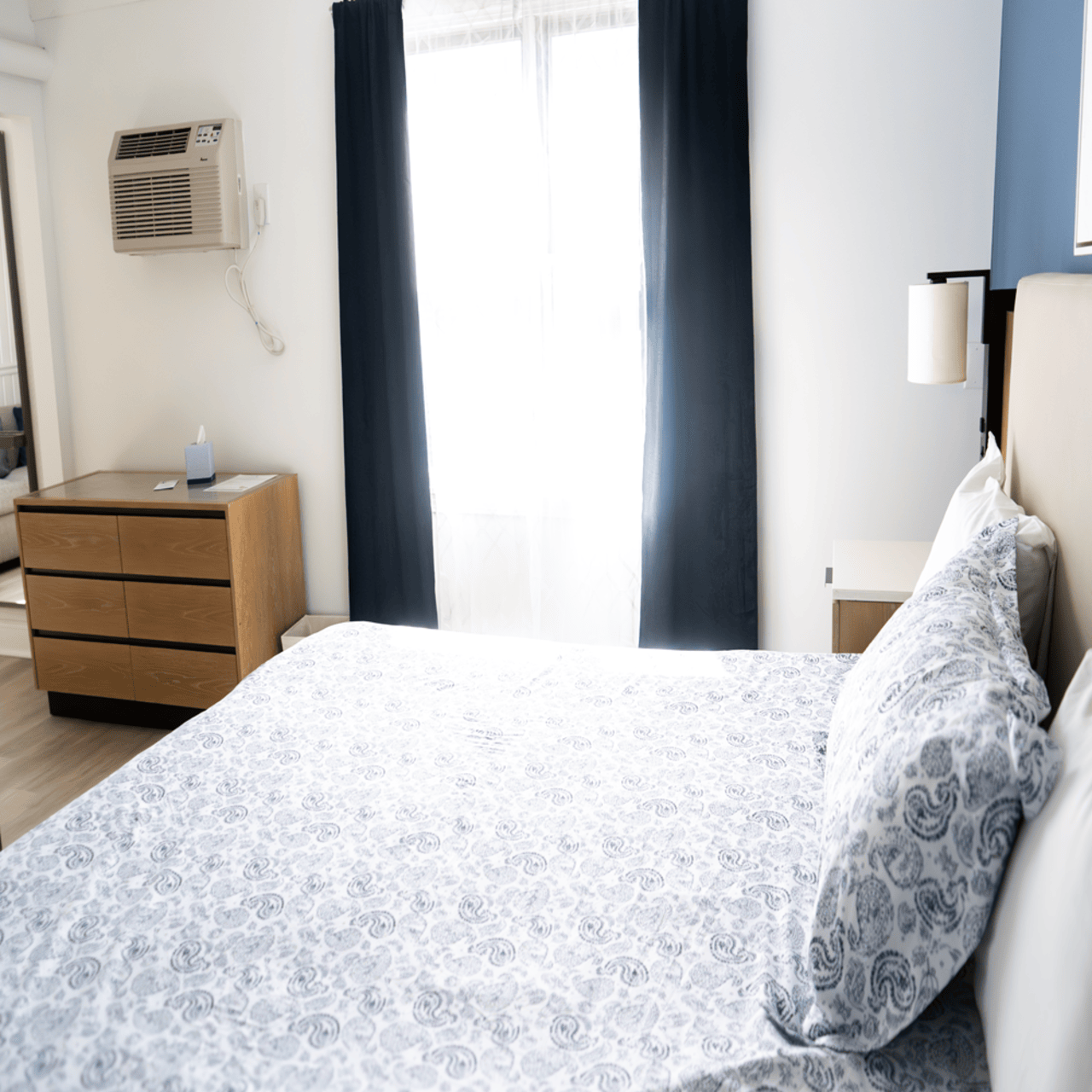 A hotel room with two beds and a blue wall