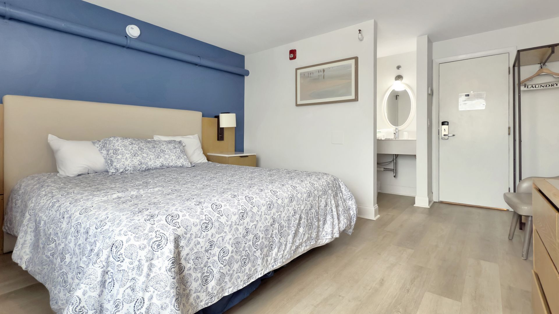Hotel room with a bed, sink, and closet. Blue and beige color scheme.