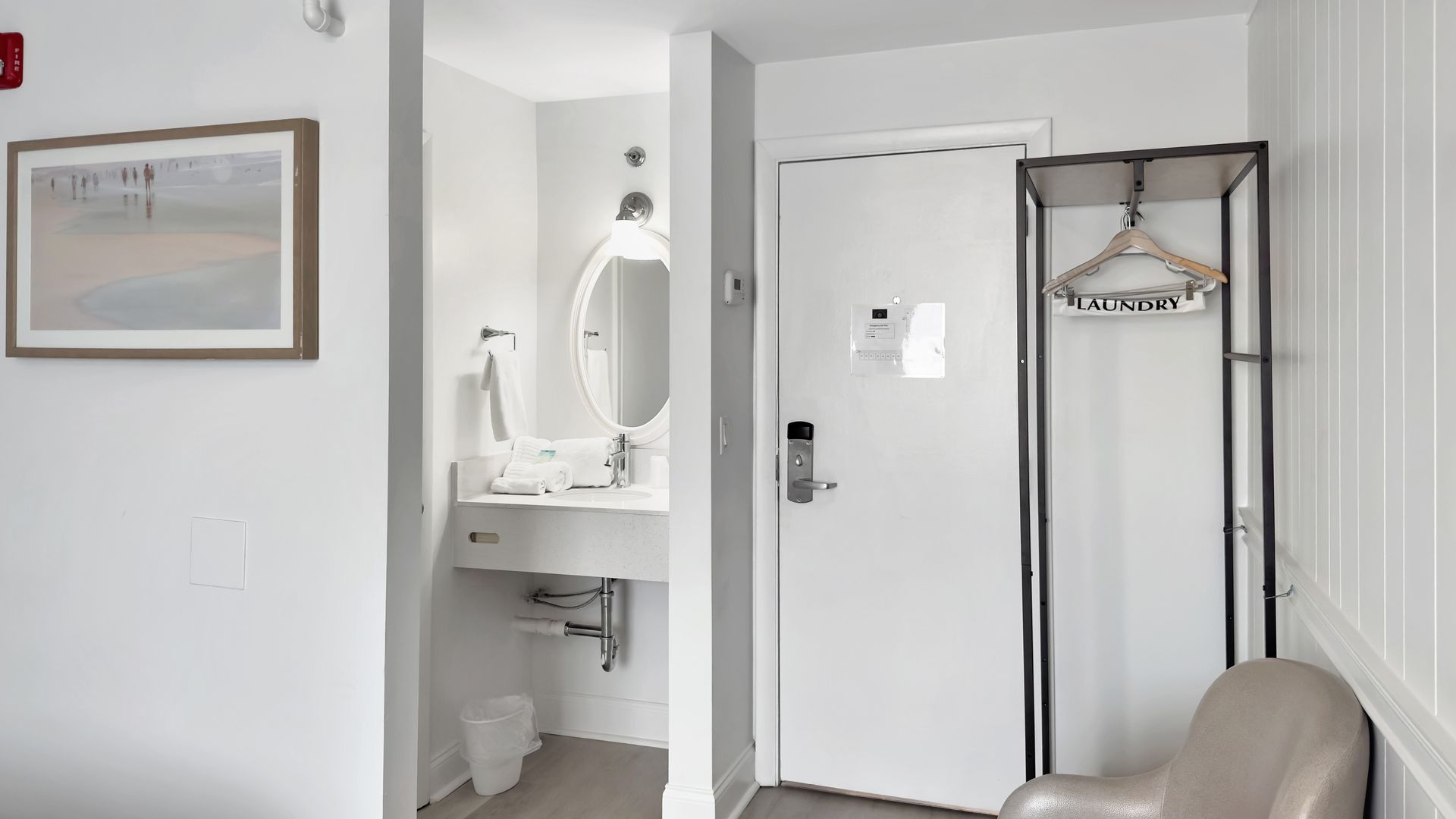 Hotel room interior with white walls, bathroom, door, and coat rack.