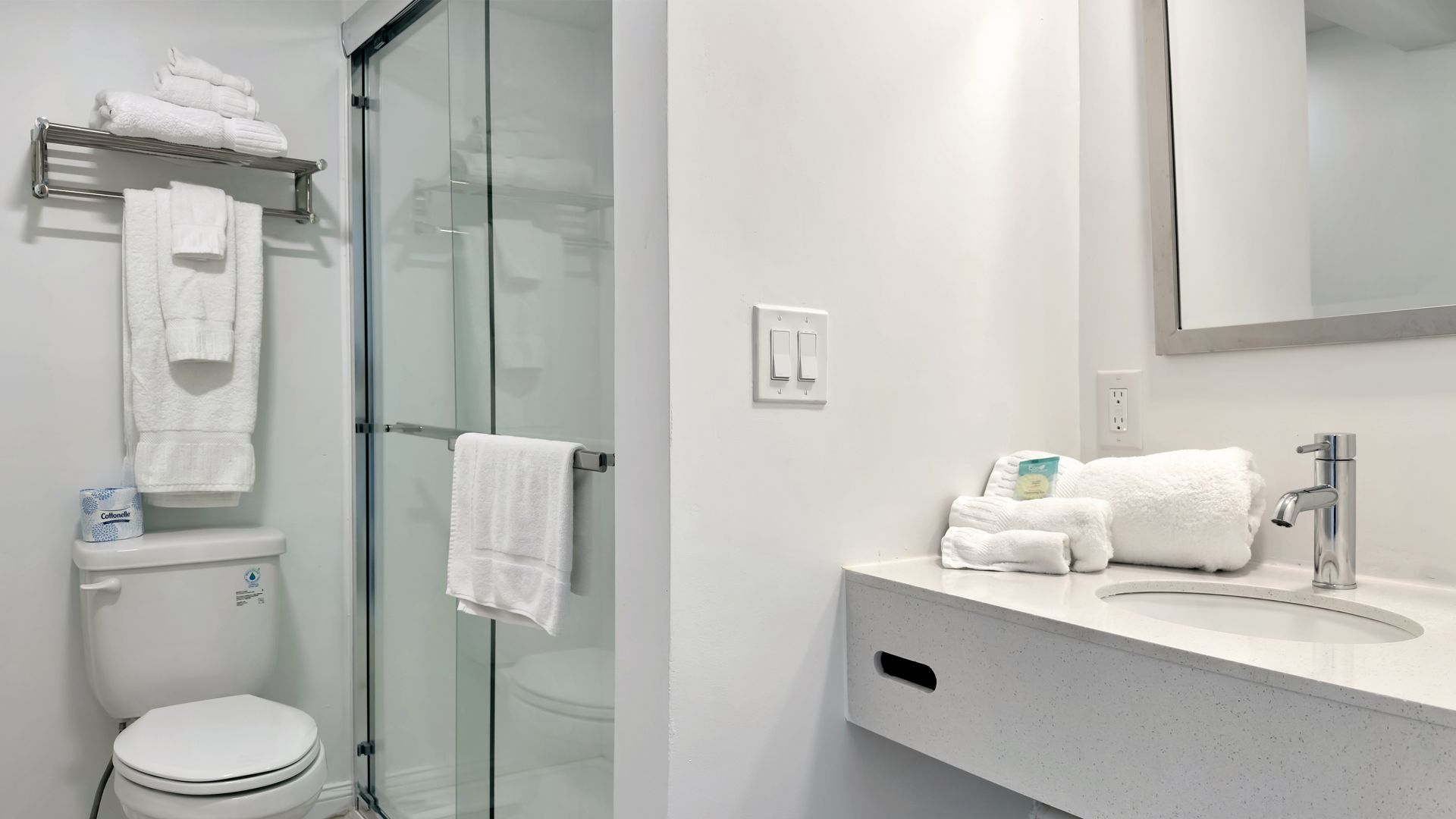 Small, white bathroom with a toilet, shower, and sink; clean, modern design.