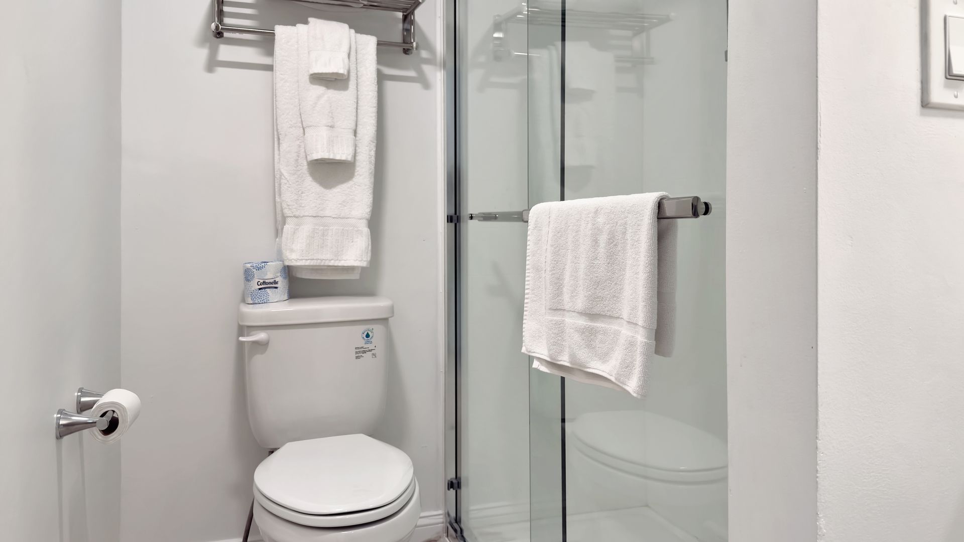Bathroom with white toilet, shower, and towels.