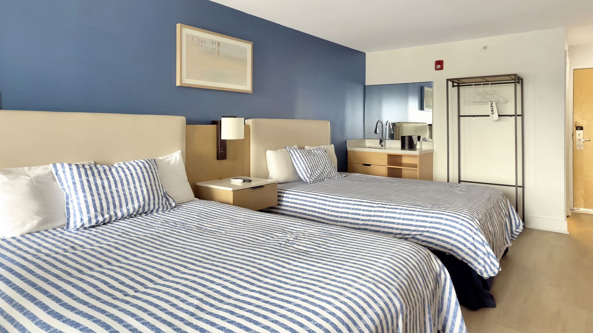 Two hotel beds with blue striped bedding in a room with blue walls.