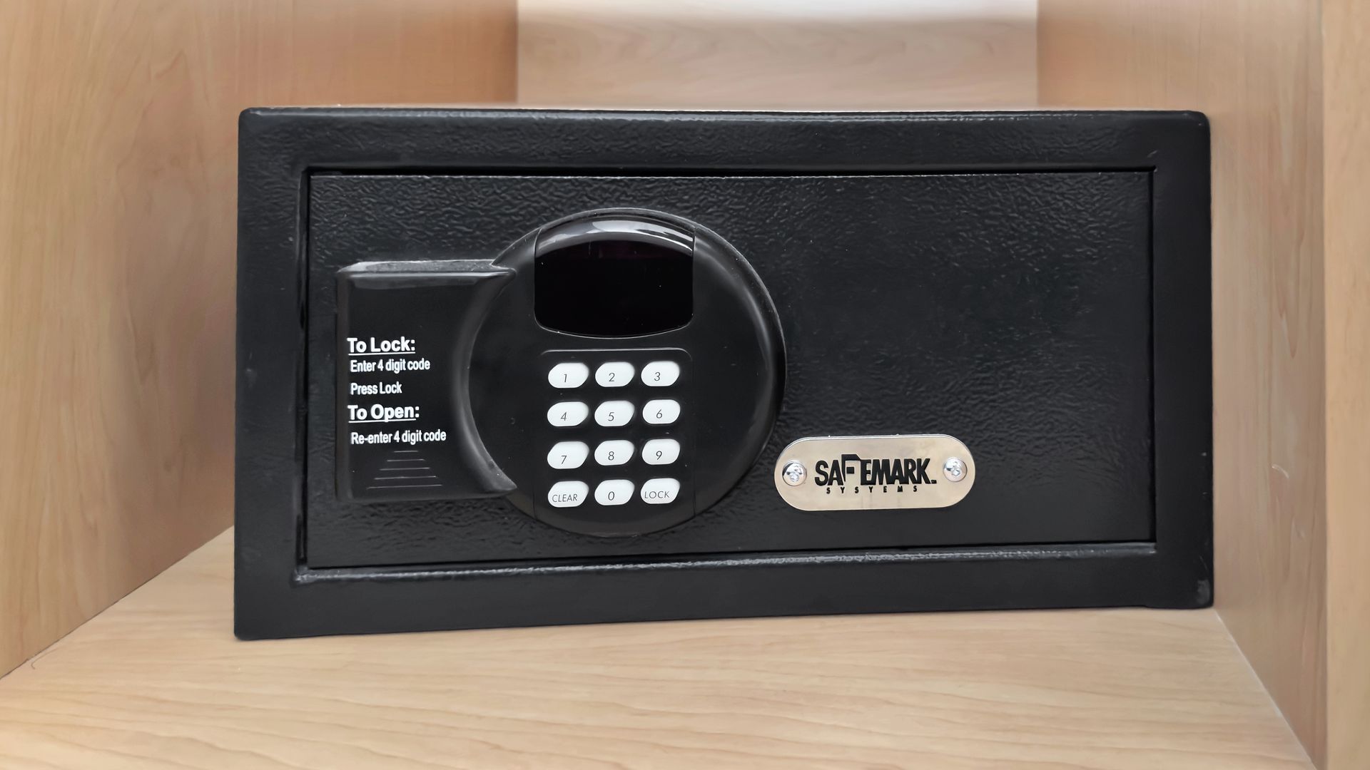 Black electronic safe on a shelf with number keypad and brand label.