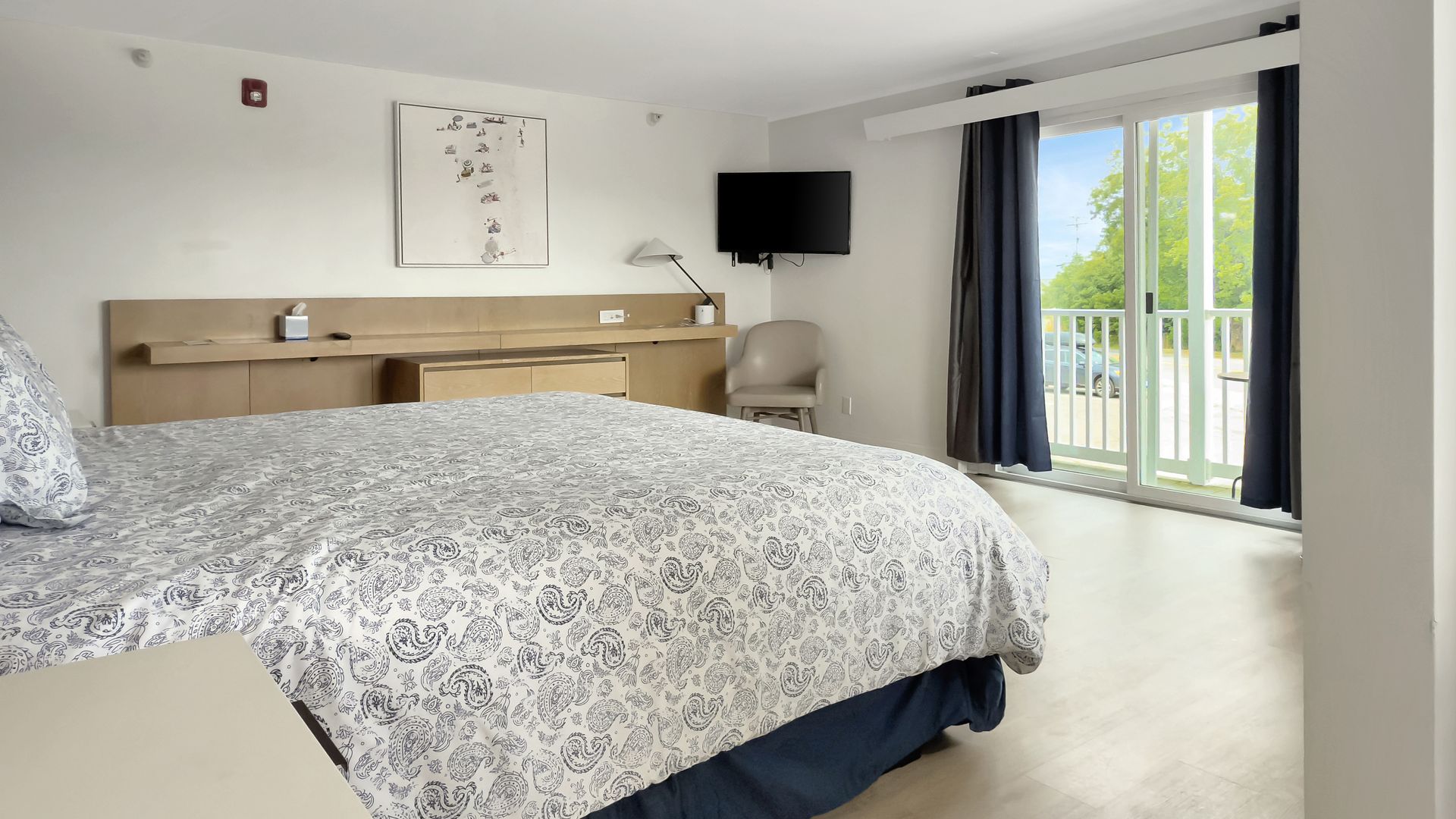Bedroom with a bed, TV, and sliding door to a balcony with a view.