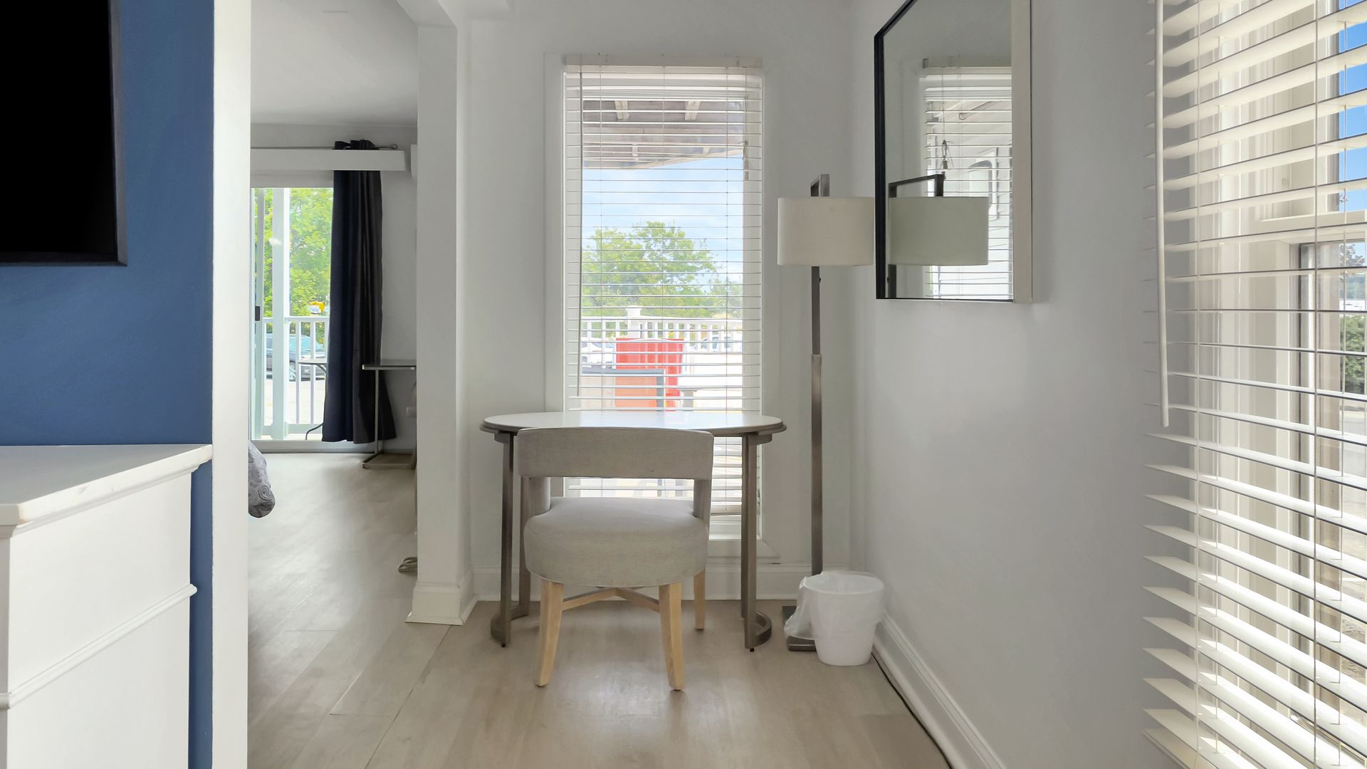 A bright white hallway with a small desk, chair, and window overlooking a deck.