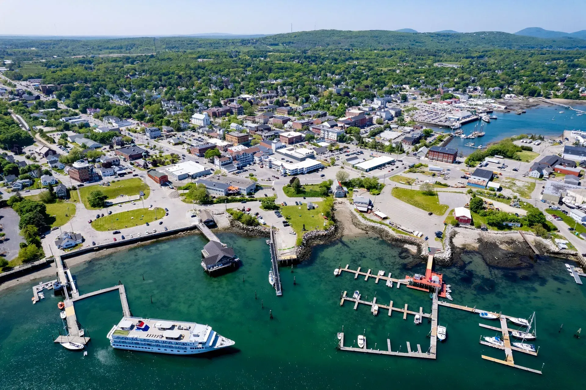An aerial view of a harbor with boats docked and a city in the background