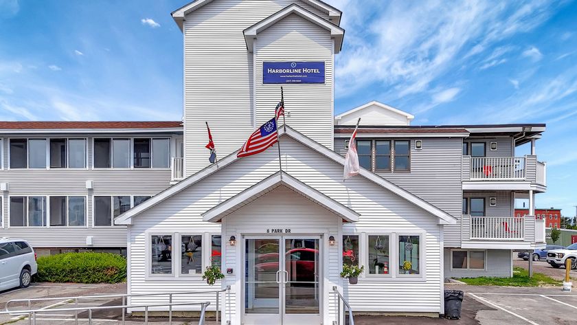 White building with a peaked entrance, flags, and sign