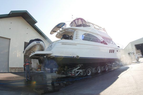 A large white boat is sitting on a trailer in front of a building.
